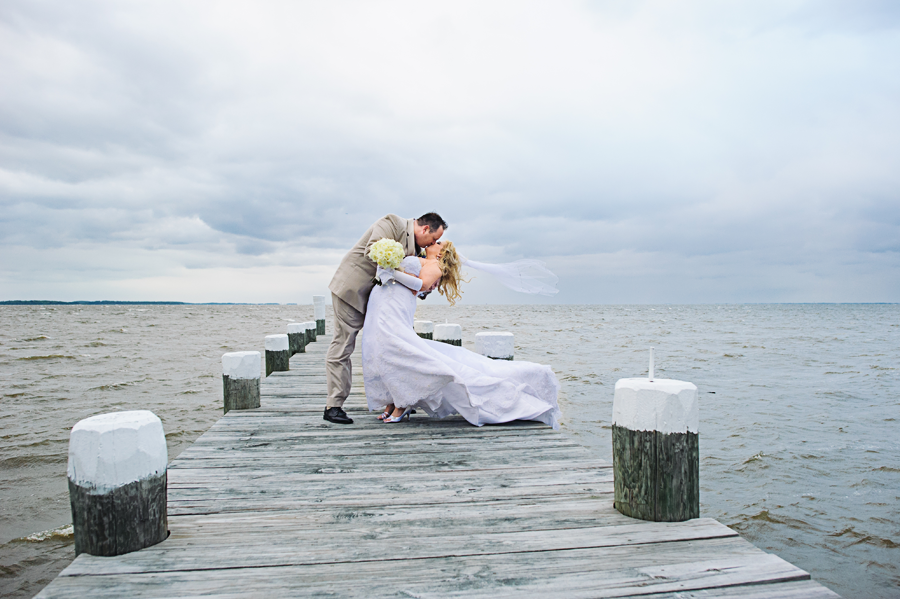 Groom dipping Bride on pier