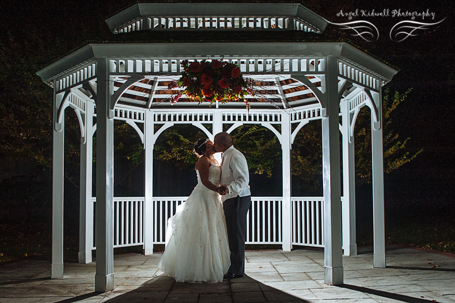 bride and groom kissing under a gazebo at grey rock masion