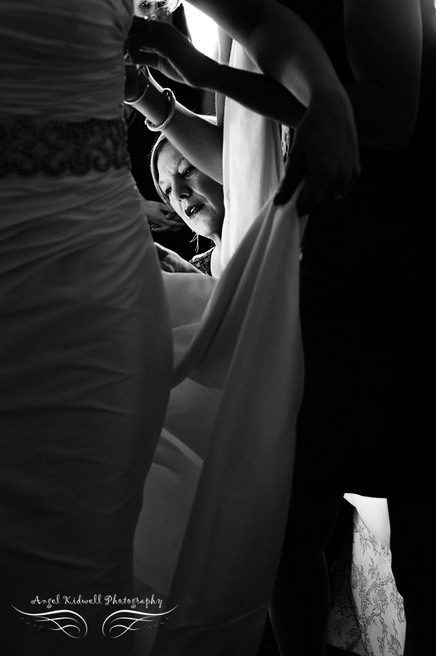 mother of the bride helping her daughter put her wedding dress on