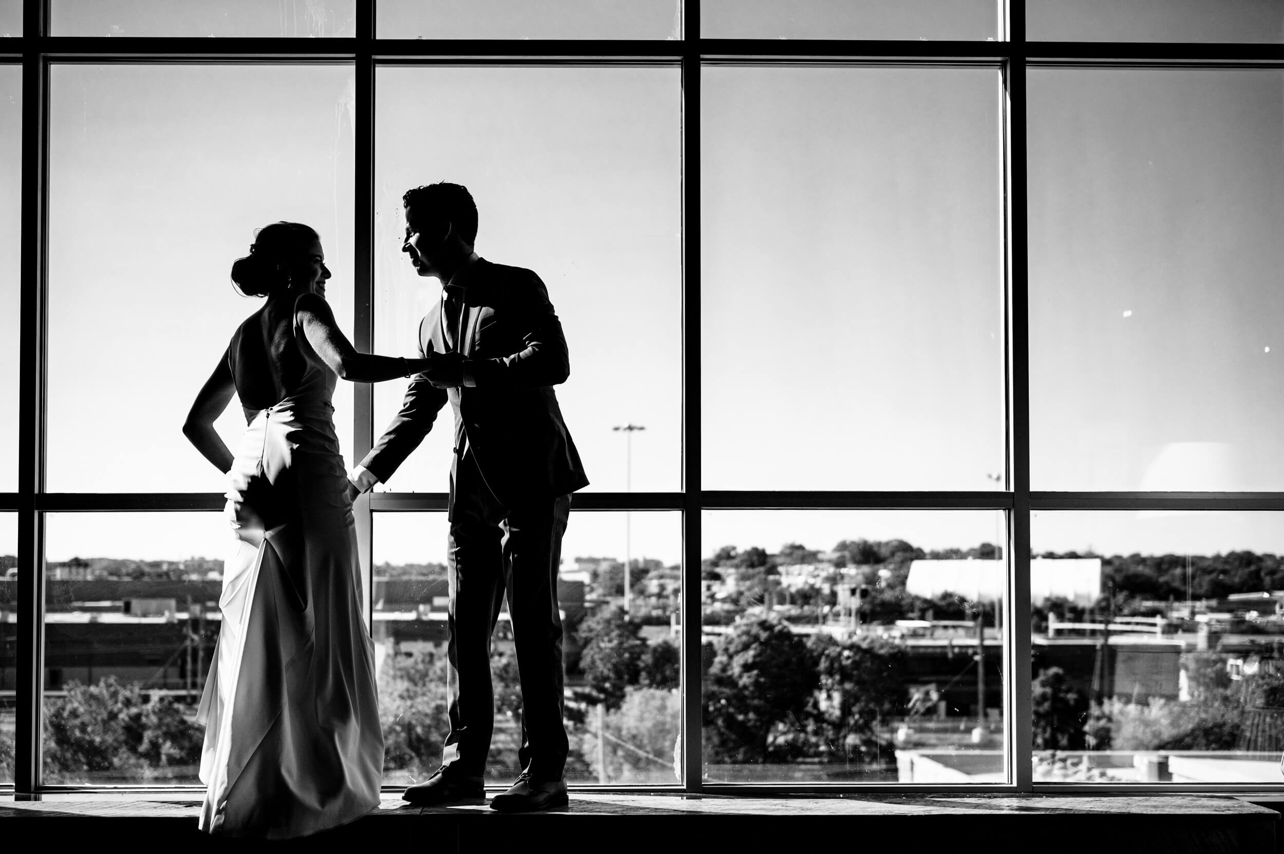 groom helping his bride step up at to a large window at a washington dc wedding venue