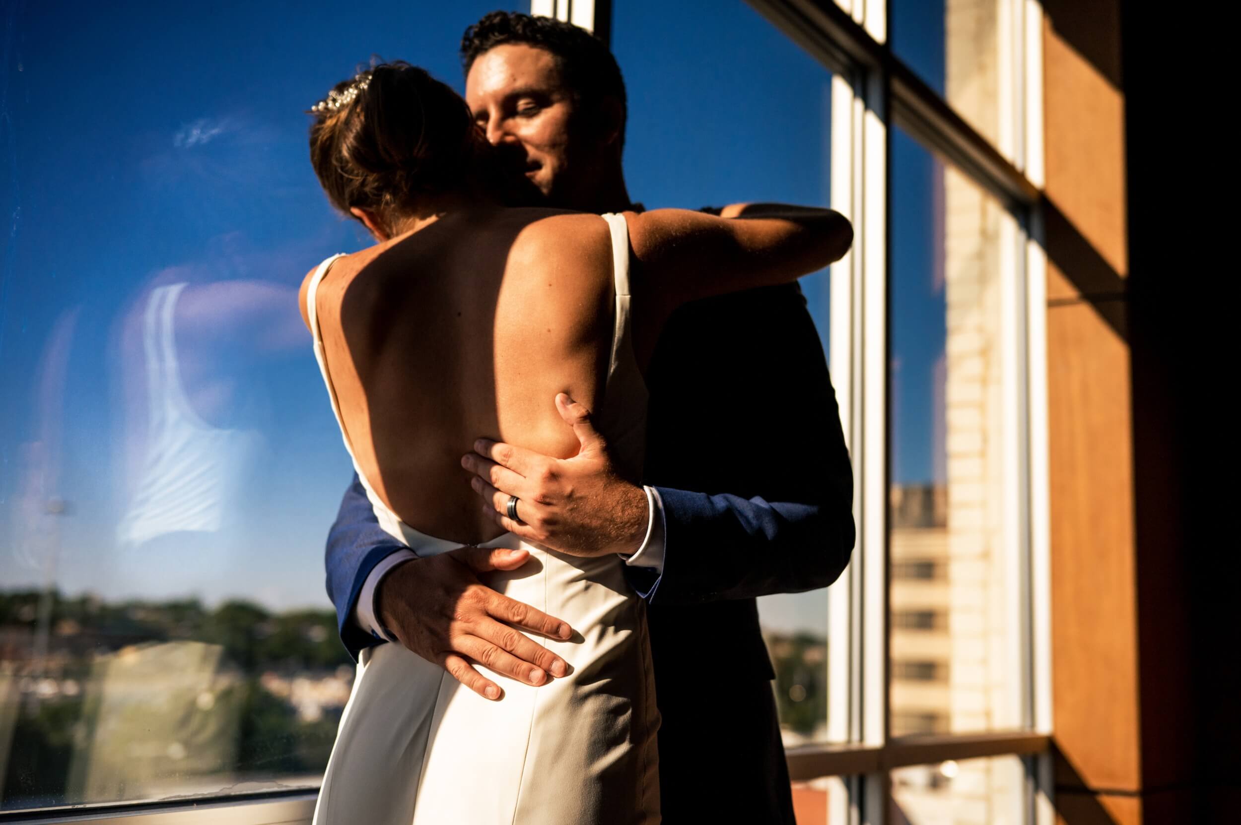 bride and groom hugging in front of a window at a washington dc winery wedding venue