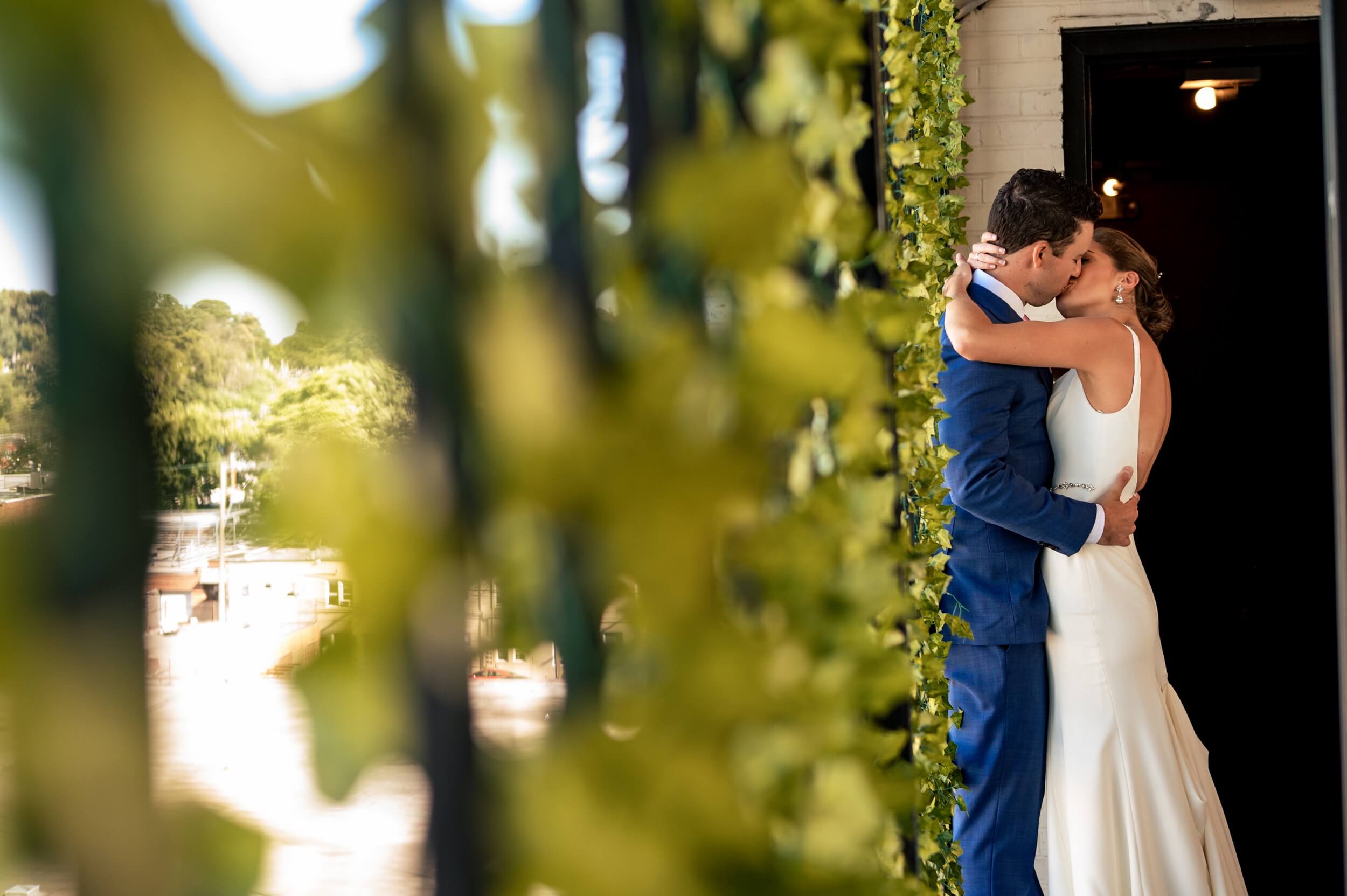 bride and groom kissing in front of an ivy wall at dc wedding venue