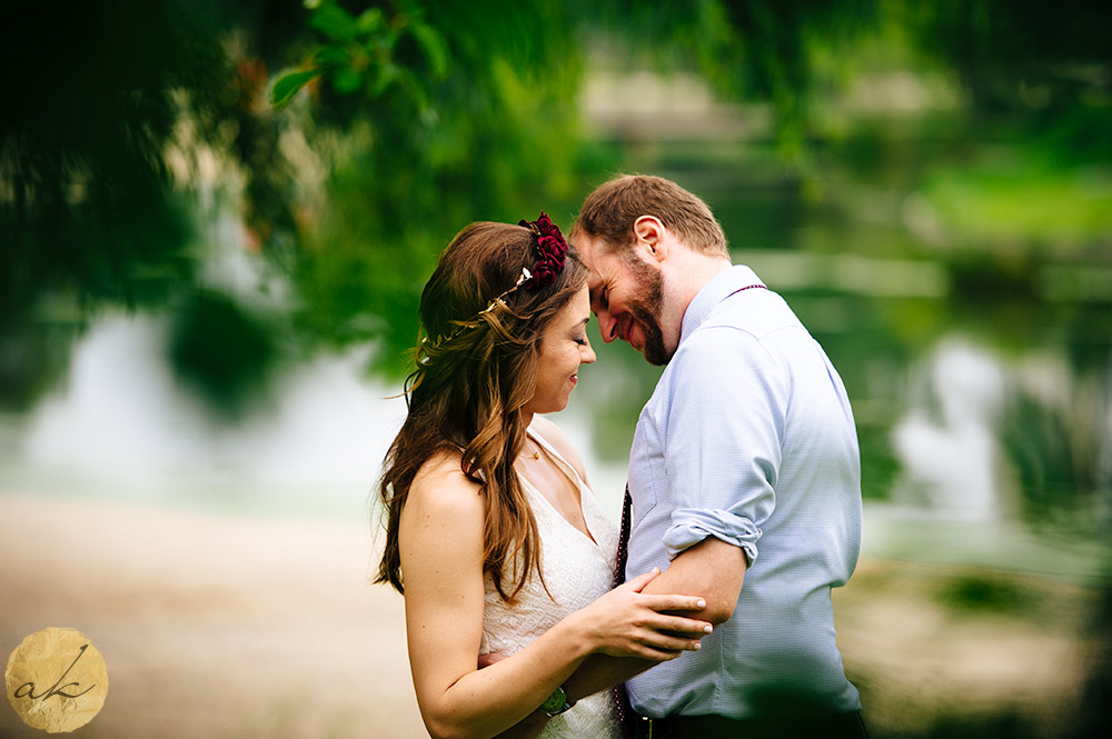 couple snuggling closely with greenery in the background