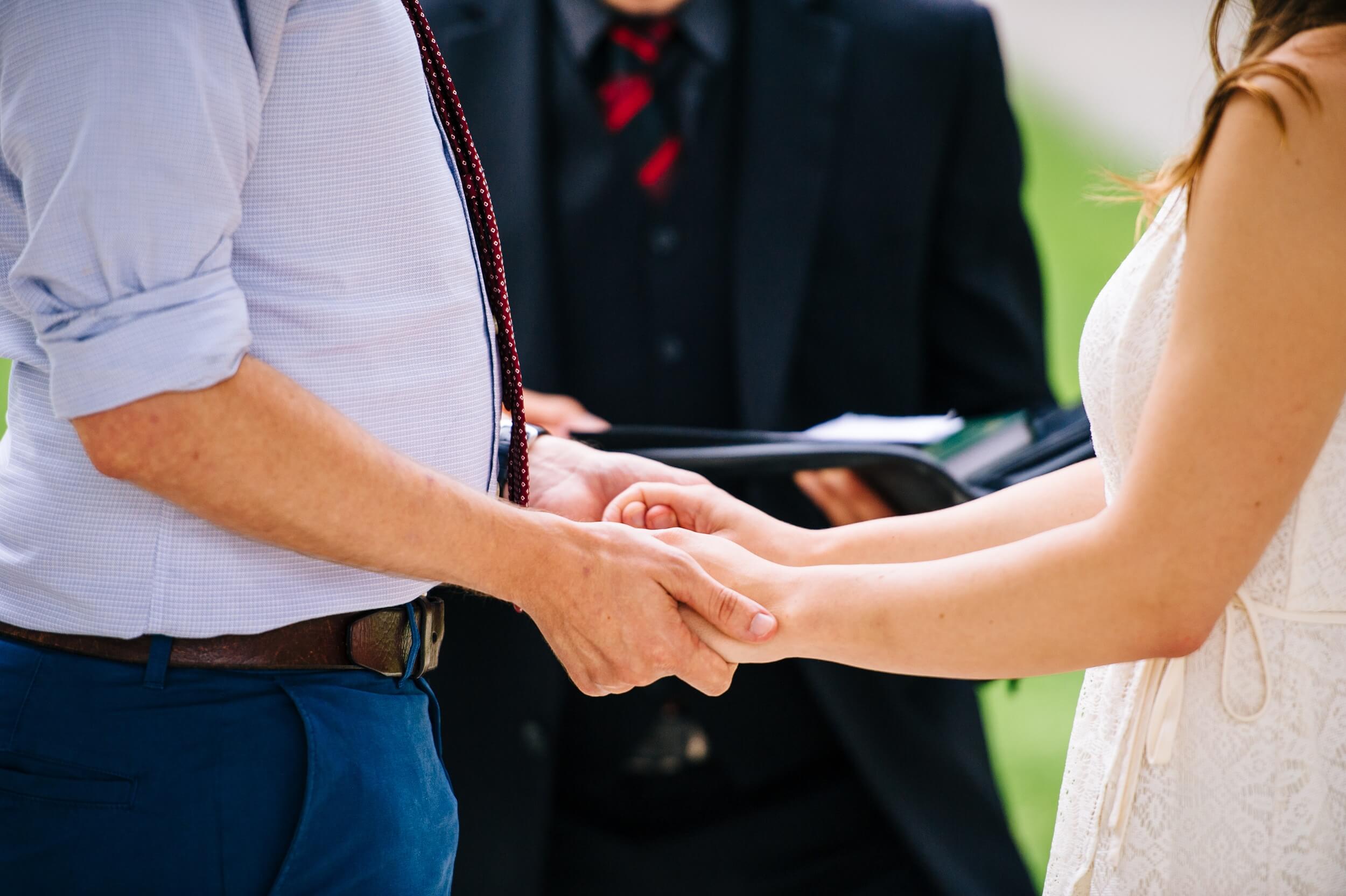 close up photo of couple holding hands exchanging vows