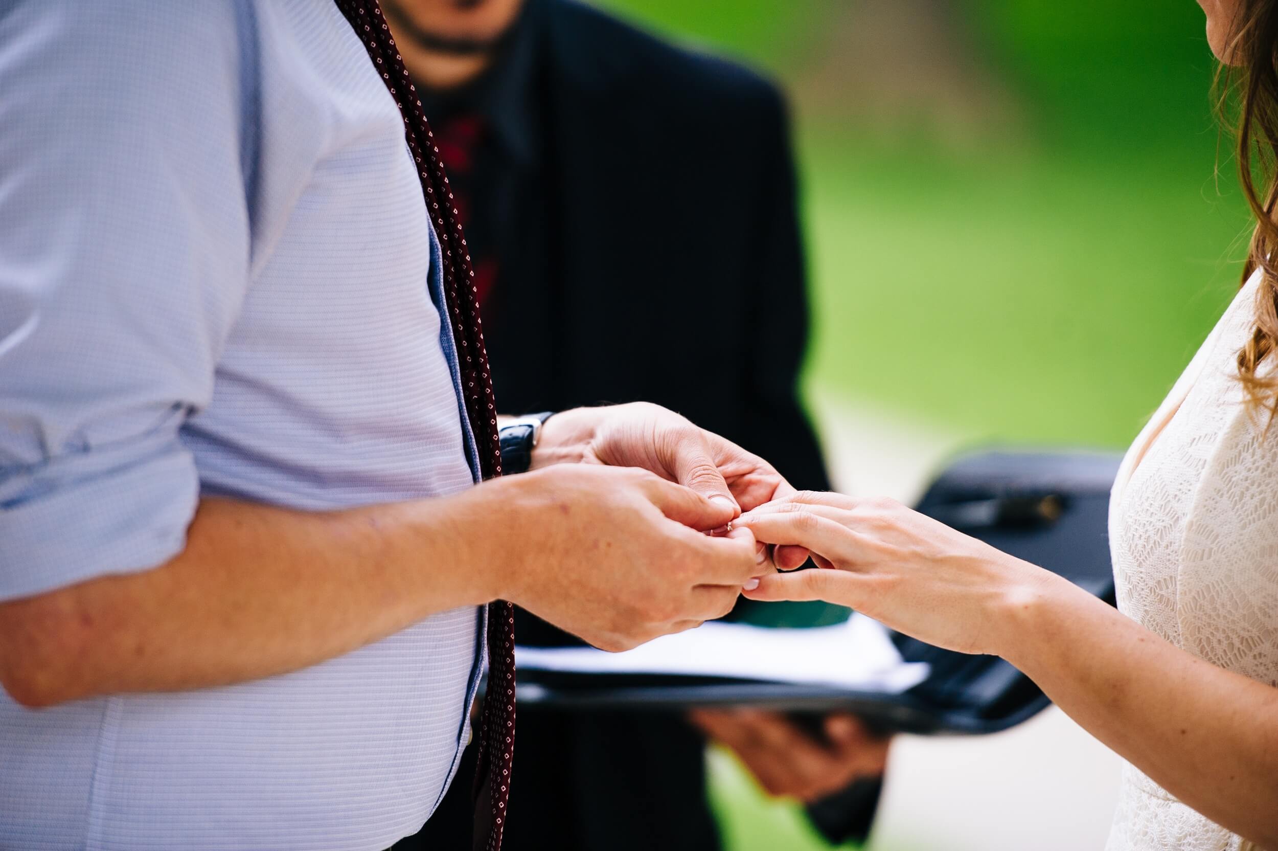 groom putting wedding band on bride