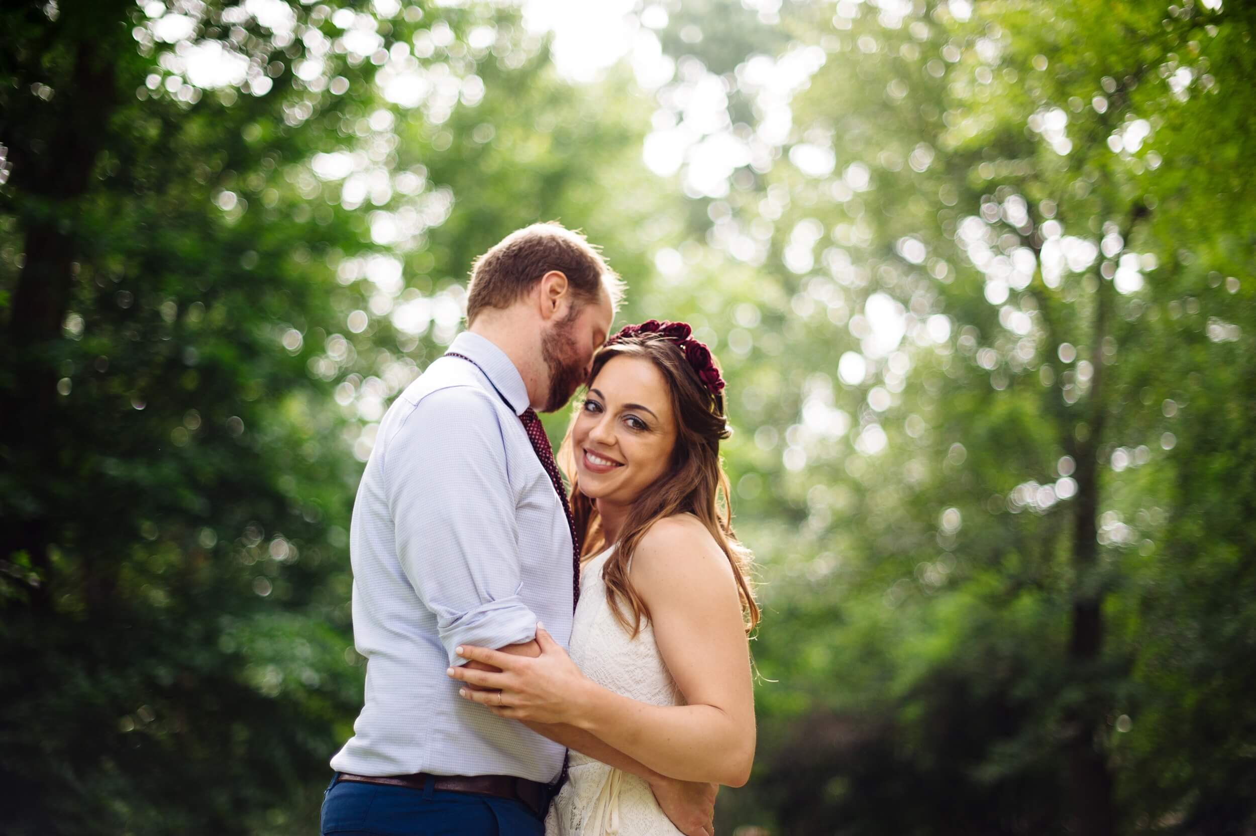 groom nuzzling bride who is smiling and looking at the camera