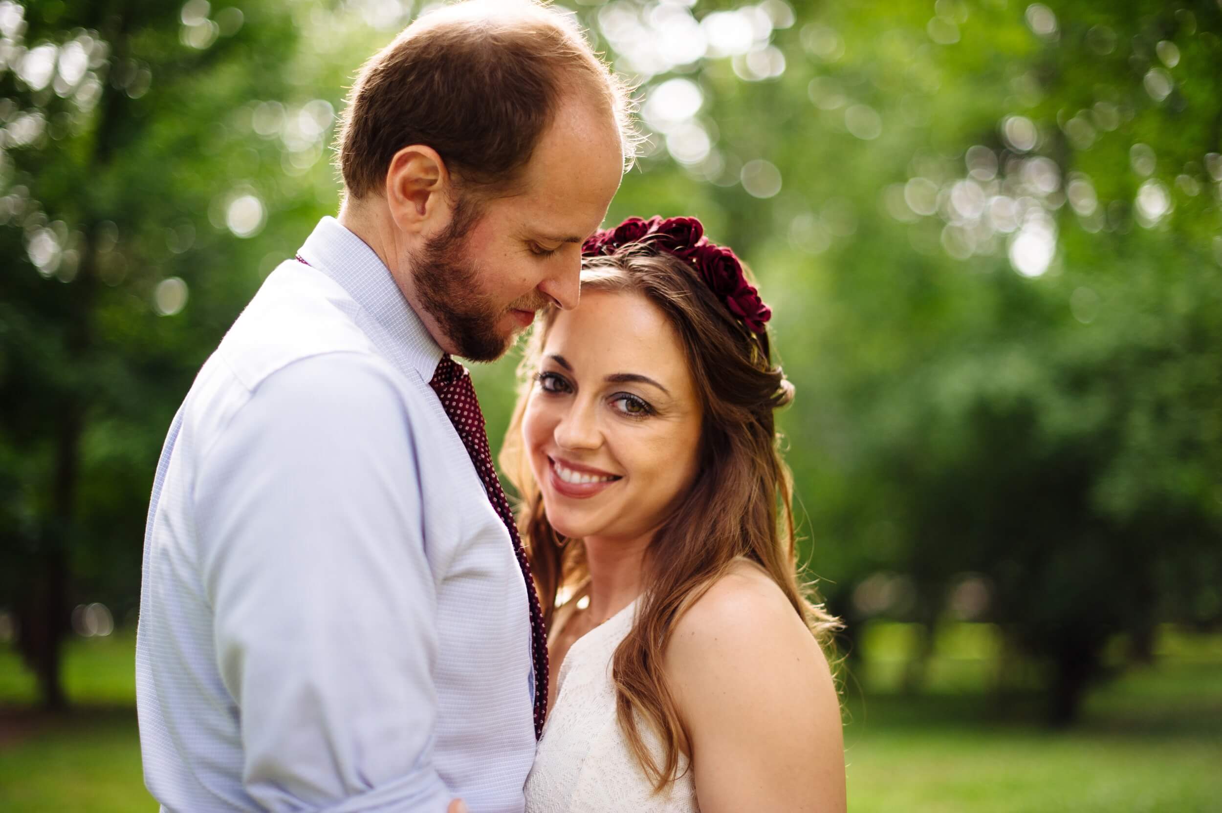 groom nuzzling bride who is smiling and looking at the camera