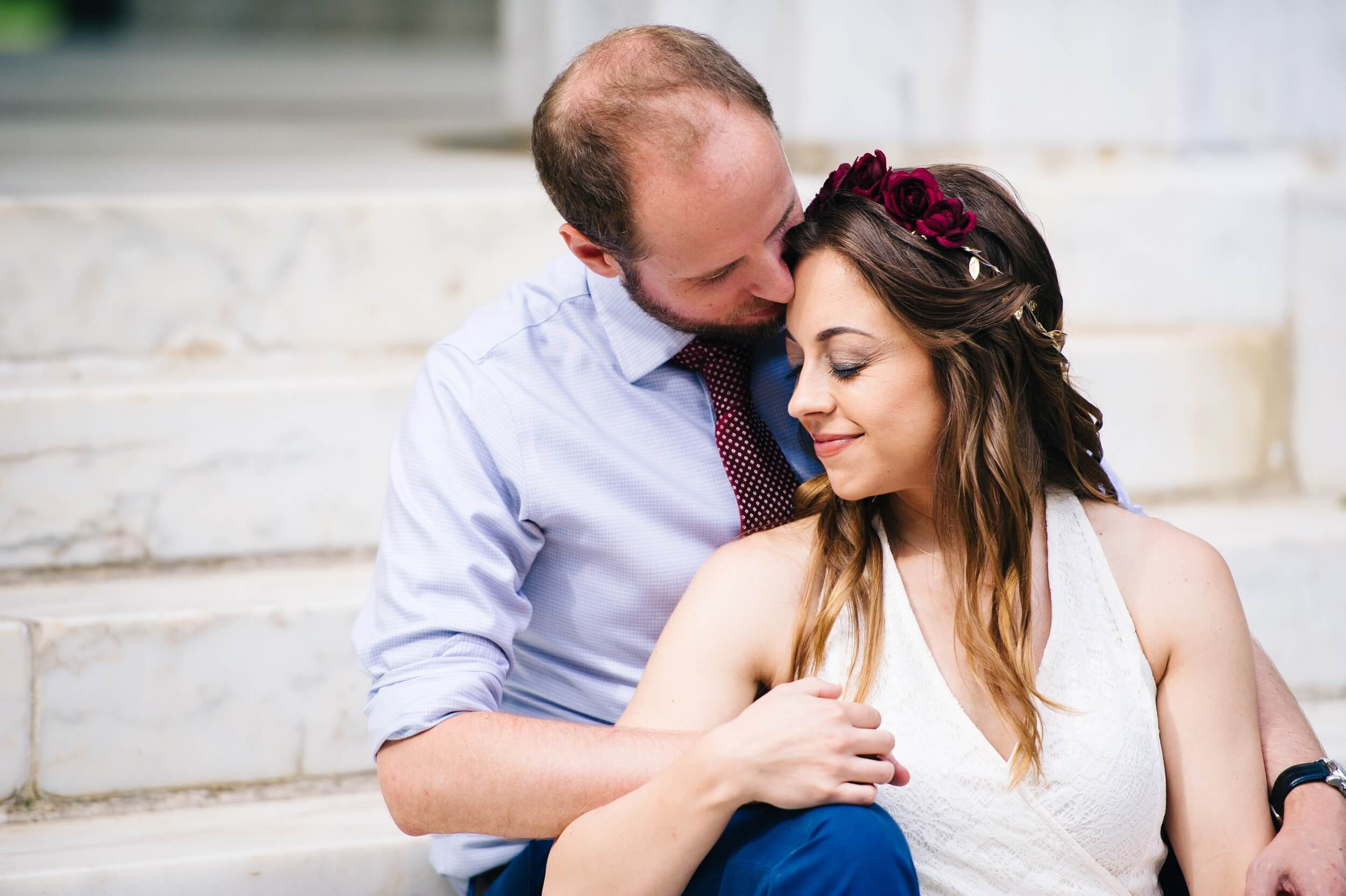 couple sitting on the steps of the dc war memorial snuggling