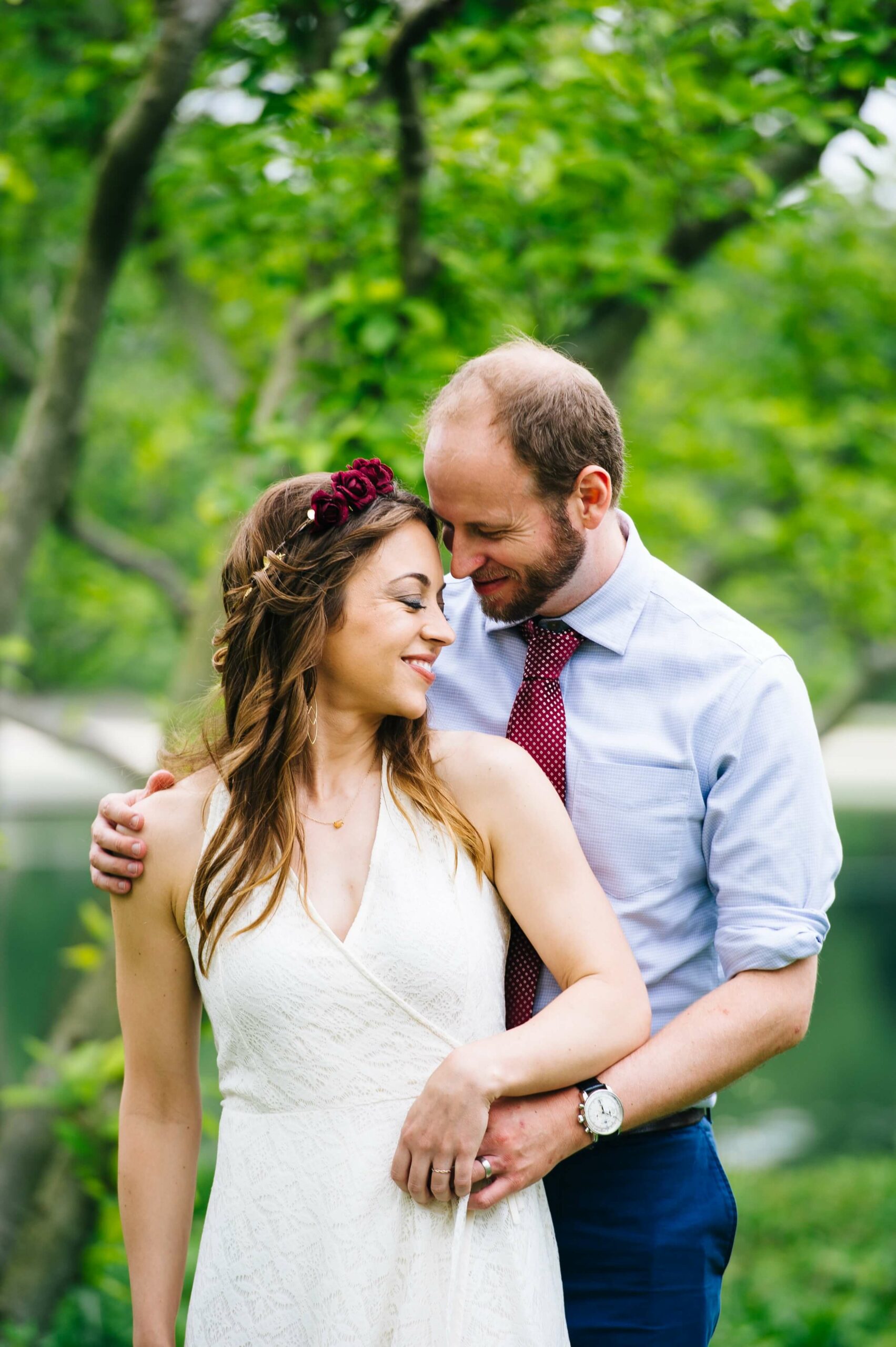 portrait of bride and groom snuggling with greenery in the background
